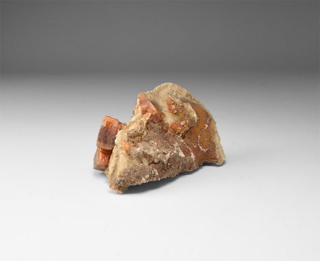 A fine specimen of wulfenite with two prominent cubic crystals to one side of matrix, in white card tray with label reading '