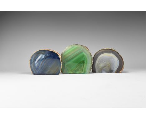 A group of three cut and polished banded agate specimens, one dark blue, one pale grey and violet, one green, all colour enha