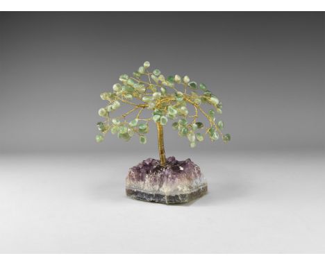 A medium size gemstone tree consisting of a brass trunk and branches tipped with polished green agate, mounted on a section o