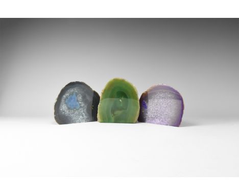 A group of cut and polished agate geodes, one purple and one dark blue with honeycomb crystals, and one banded green, colour 