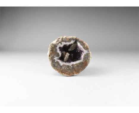 An agate geode filled with purple amethyst crystals with accessory brown calcite. 672 grams, 10.7cm (4 1/4"). From the histor