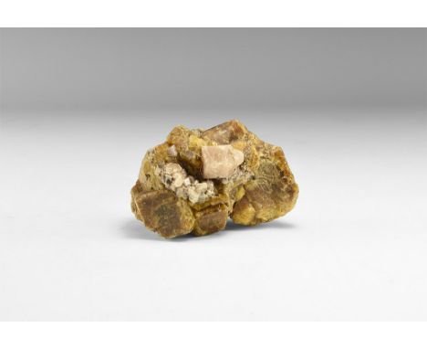 A fine mineral specimen comprising of pale pink grossular garnet and brown vesuvianite crystals, in white card tray with labe