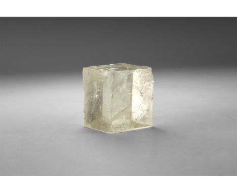A large cleavage rhombohedron of yellowish Iceland spar specimen with rainbow reflections, in a white card tray with label re