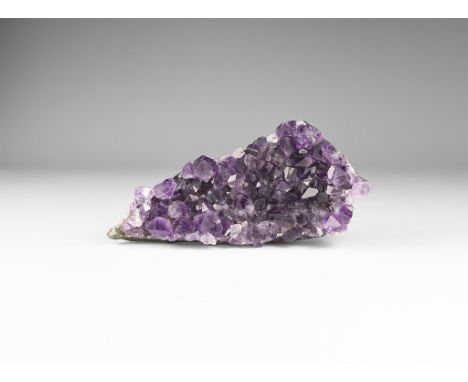 A fine specimen of dark purple amethyst crystals on matrix, in white card tray with label reading: 'AMETHYST, Antigas, Uragua
