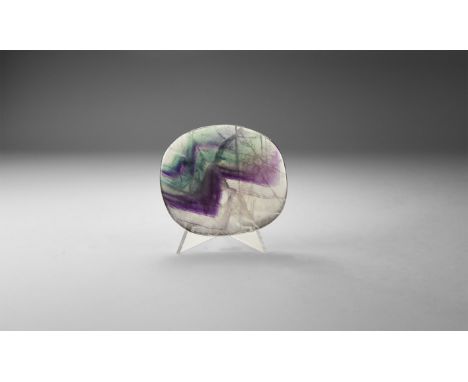 An oval polished specimen of fluorite, with purple and green colour; natural fractures to the body with 'rainbow' reflection.