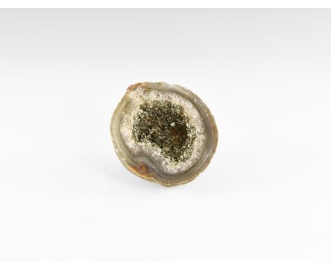 A cut and polished geode displaying bands of colour and crystal growth to the edges and artificially added clusters of pyrite