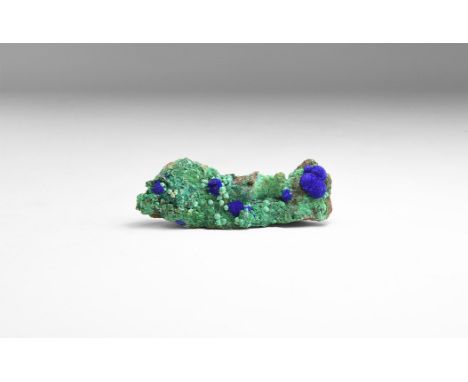 A specimen of malachite on matrix with a spherical azurite aggregates to the surface, in white card tray with label reading: 