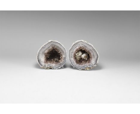 A pair of cut geode with bands of pale blue agate and formation of dark purple amethyst crystals to the centre with accessory