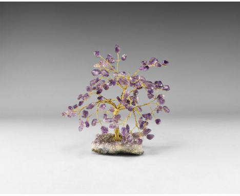 A medium size gemstone tree consisting of a brass trunk and branches tipped with polished amethysts, mounted on a section of 