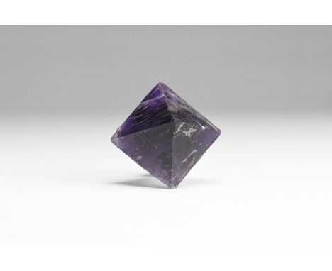 A dark purple fluorite cleavage octahedron, some chips to the surface; in a white card box with old label reading: 'FLUORITE 