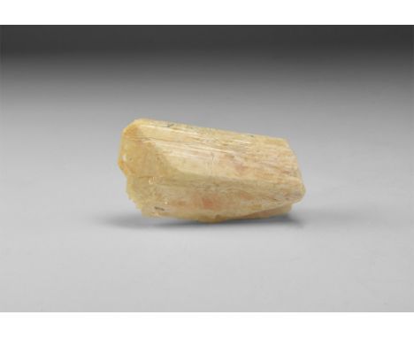 A slightly orange danburite crystal in white card tray with label reading: 'DANBURITE, Charcas, San Luis Potosi, Mexico'. 41 