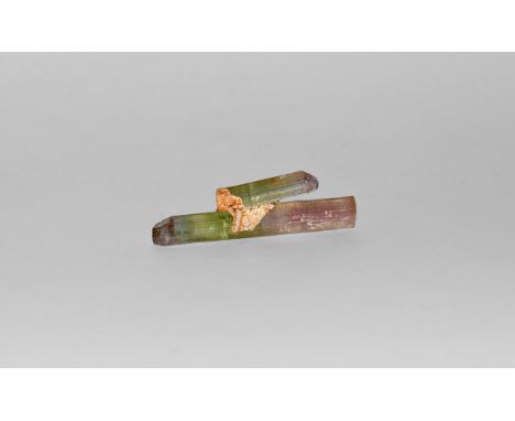 A very fine specimen of two joined tourmaline columns with shades of pale green and red. 5 grams (25 carats), 43mm (1 3/4"). 