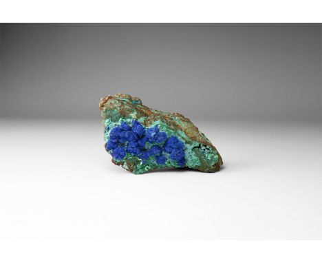 A specimen of malachite on matrix, with a cluster of spherical azurite aggregates to one side, in white card tray with label 
