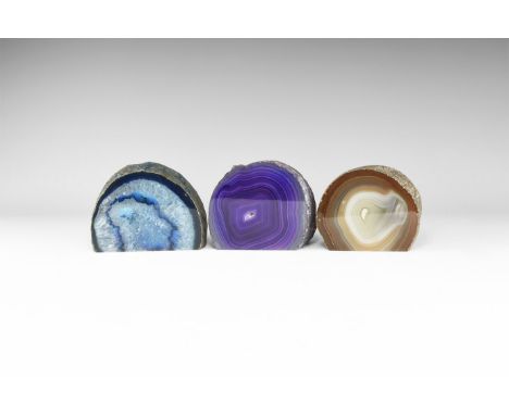 A group of three cut and polished banded agate slices, one brown, one deep blue and one purple; colour enhanced. 1.04 kg tota