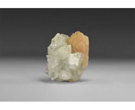 A large piece of apophyllite with clear colour and rainbow reflections and with a pale orange stilbite crystal to one side, i