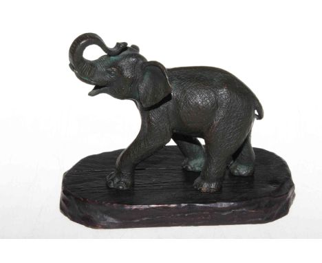 A Japanese Meiji period well detailed bronze elephant with raised trunk, on wooden stand, 15cm.
