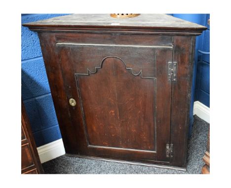 A George III oak corner cupboard, of broad proportions, outswept cornice above a panel door enclosing a shelf, circa 1760, 91