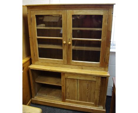 A stripped pine kitchen cabinet, two glazed doors enclosing shelving to top, projecting base, two sliding panel door cupboard