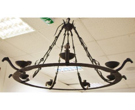 A wrought iron seven light chandelier with stylised ram head terminals