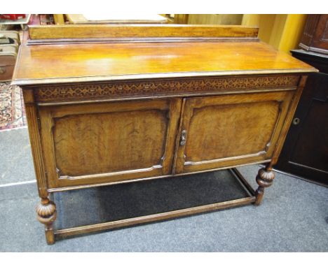 An early 20th century oak sideboard, moulded frieze, shaped fielded panel doors, enclosing central bank of three drawers flan