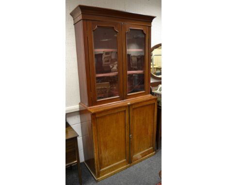 A Victorian mahogany library bookcase, outswept cornice above a pair of glazed doors enclosing two shelves, the projecting ba