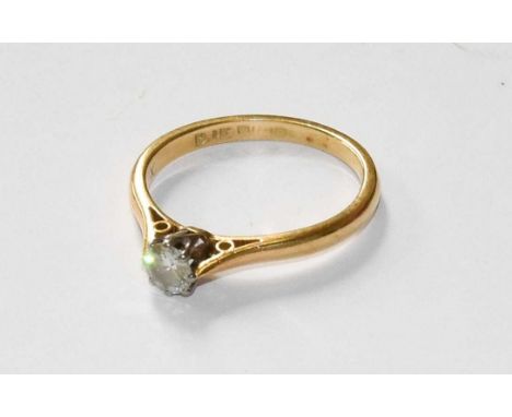 An 18 Carat Gold Diamond Solitaire Ring, the round brilliant cut diamond in a white claw setting, to a yellow plain polished 