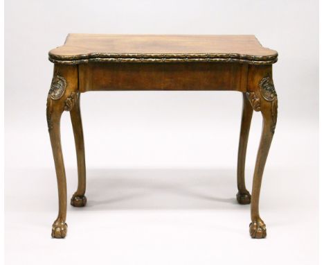 A GEORGE II DESIGN MAHOGANY FOLD-OVER TOP CARD TABLE, with carved edges, green baize cover and counter wells, and supported o