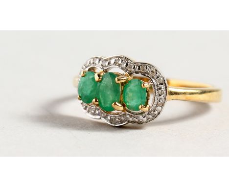 A 9CT GOLD THREE STONE EMERALD AND DIAMOND RING.