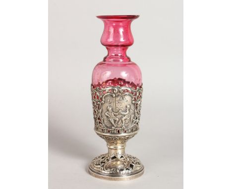 A STERLING SILVER AND RUBY GLASS VASE, repousse with Dutch scenes.