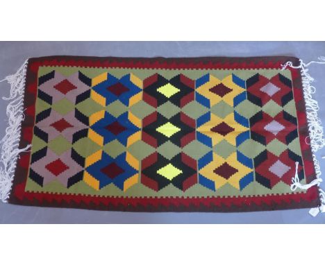 A Persian hand-made kelim, repeating geometric motifs on a light green ground, 91 x 65cm 