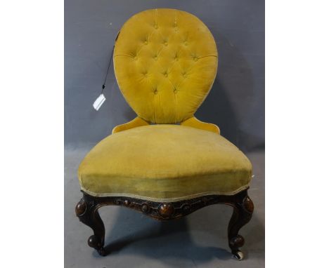 A Victorian mahogany spoon back nursing chair, button back yellow velvet upholstery, on carved legs and castors, H.89cm 