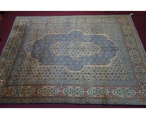 A Central Persian Kirman carpet with central diamond double pendant, with repeating petal motifs, surrounded by repeating sty