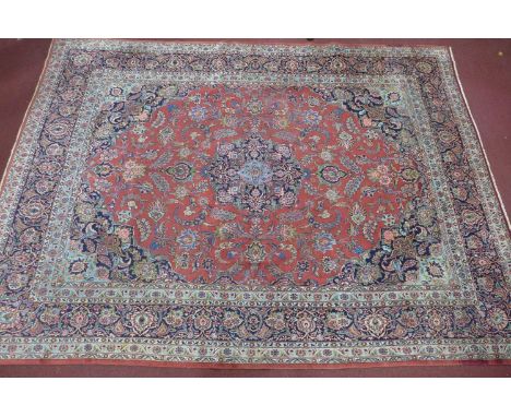 A Persian Kashan carpet, central floral medallion and stylised floral motifs on a rouge field, within stylised floral border 