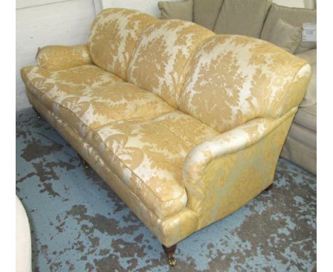 SOFA, Howard style, three seater, with gold floral patterned upholstery, on short turned front supports with castors, 214cm L