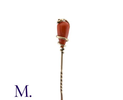 A Coral Snake Stick Pin in yellow gold, comprising a polished coral drop encased in a coiled snake motif. Unmarked but tests 