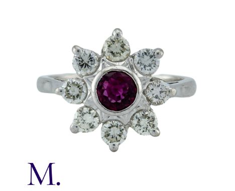 A Ruby And Diamond Cluster Ring in 18k white gold, set with a central round cur ruby within a border of round cut diamonds, a