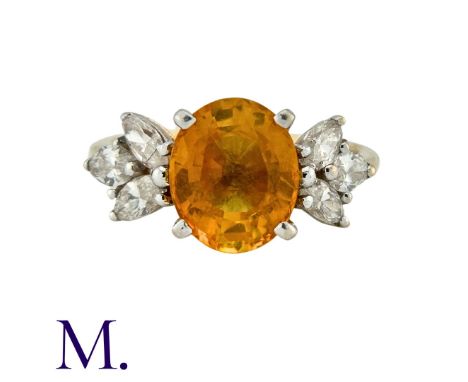 A Sapphire and Diamond Ring in 14K yellow gold, set with an oval cut yellow-orange sapphire of approximately 2.0ct with six m