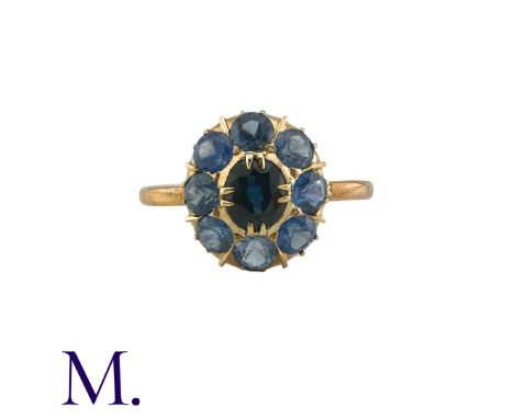 A Sapphire Cluster Ring in yellow gold, comprising a cluster of round cut sapphires surrounding a principal oval cut sapphire