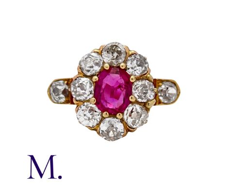 A Ruby & Diamond Cluster Ring in rose gold, set with a principal oval cut ruby of approximately 0.50cts, within an old cut di