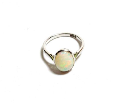 An opal ring, the oval cabochon opal in a white millegrain setting to a tapered shoulder plain polished shank, finger size K.