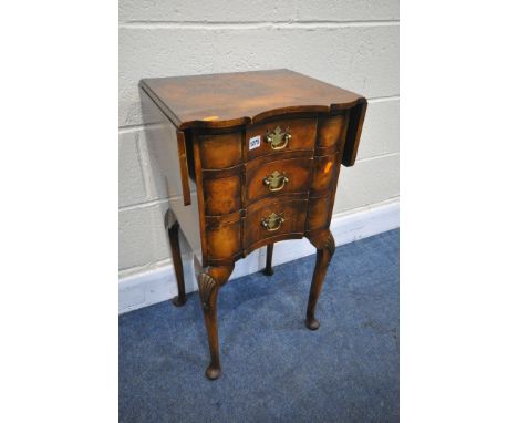 A REPRODUCTION WALNUT DROP LEAF LAMP TABLE, with three drawers, on cabriole legs, open width 71cm x depth 41cm x depth 34cm x