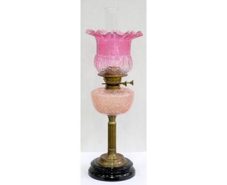 AN EDWARDIAN BRASS OIL LAMP, WITH REEDED PILLAR AND SEMI-OPALESCENT PINK MOULDED GLASS FOUNT, BRASS BURNER AND A SHADED CRANB