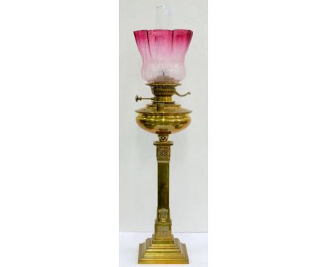 AN EDWARDIAN BRASS OIL LAMP, THE SQUARE PILLAR ON STEPPED FOOT WITH BRASS FOUNT, BURNER AND CRANBERRY TINTED AND ETCHED GLASS