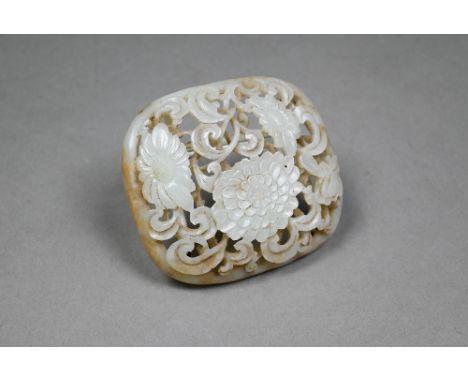 An antique Chinese jade reticulated and domed plaque, the pale celadon stone with russet inclusions carved with a floral and 