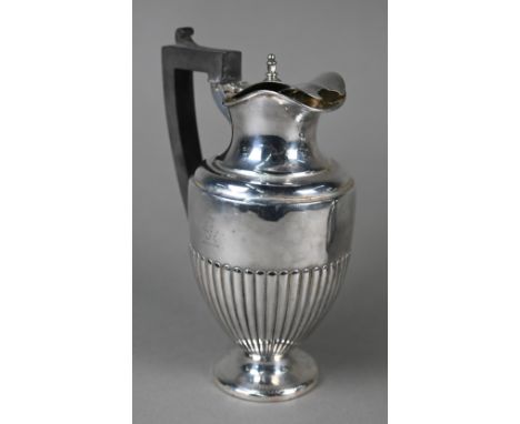 A late Victorian silver urn-shaped hot water jug with hinged lid, half-reeded body and flattened foot, composite handle, Carr