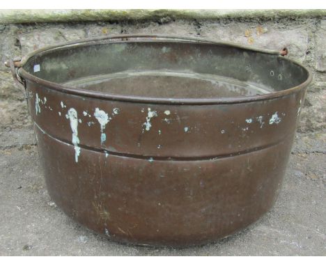 A vintage light copper cylindrical pan with loose ironwork loop handle, later adapted as a planter with drilled base, 50 cm d