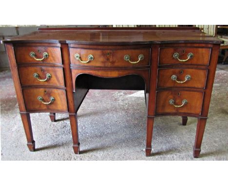 A good quality Georgian revival serpentine front, kneehole dressing table/desk fitted with an arrangement of seven oak lined 