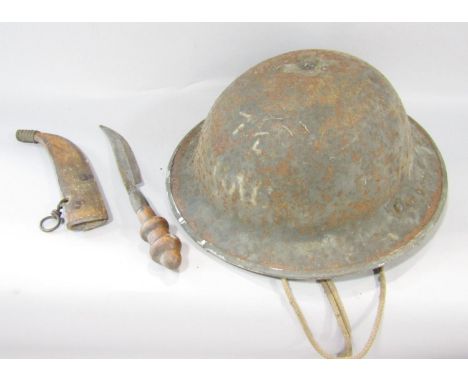 A rusty military tin helmet with original head padding and chin strap and a crude curved dagger in a leather sheath. 