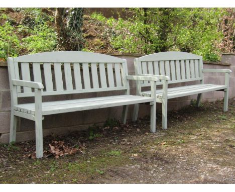 A pair of light green painted soft wood three seat garden benches with slatted seats and backs beneath arched rails, 170 cm l