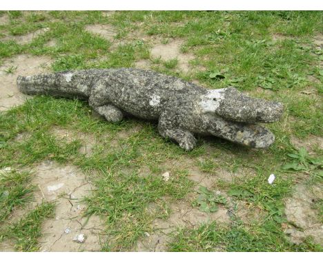 A weathered cast composition stone garden ornament in the form of an alligator 80 cm long approximately together with a conte